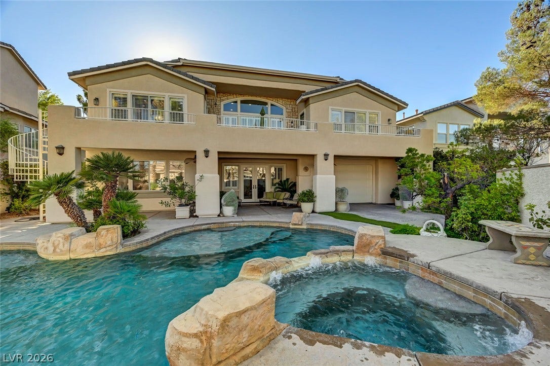 1116 Golden Age Court, Las Vegas, NV 89144 An inviting backyard oasis features a rock-scaped swimming pool and raised spa against a stucco facade.