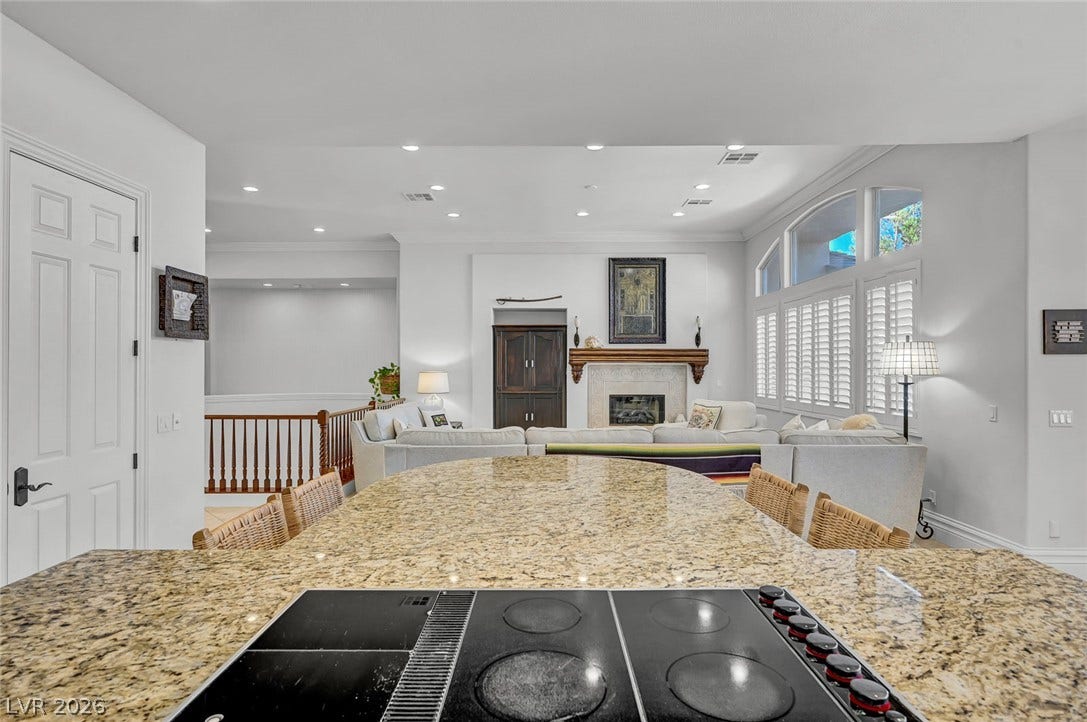 1116 Golden Age Court, Las Vegas, NV 89144 Granite countertops and an integrated cooktop overlook the open living area with a fireplace.