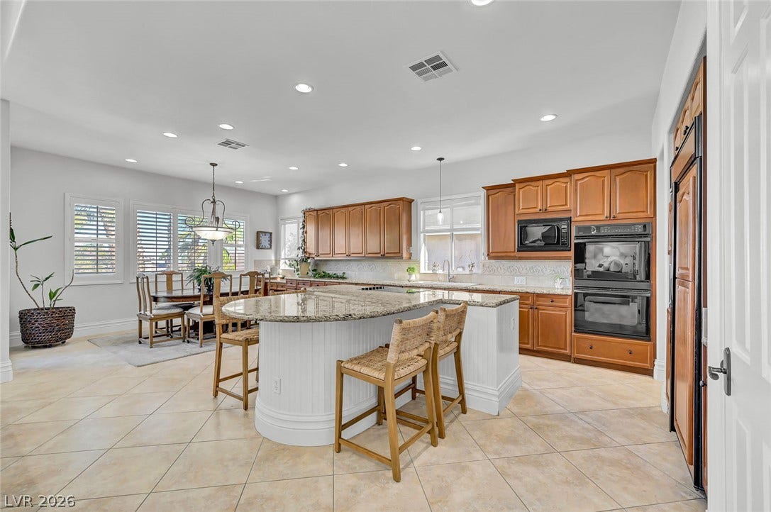 1116 Golden Age Court, Las Vegas, NV 89144 Rich wood cabinetry and expansive granite countertops define this spacious, open-concept kitchen.