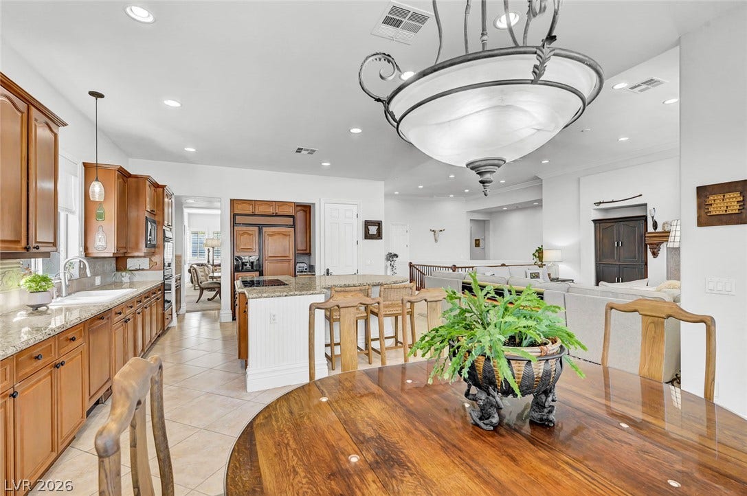 1116 Golden Age Court, Las Vegas, NV 89144 Warm wood cabinetry and granite countertops anchor this spacious open-concept kitchen.
