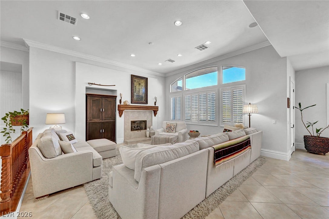 1116 Golden Age Court, Las Vegas, NV 89144 An inviting fireplace and tall arched windows define this light-filled main living space.