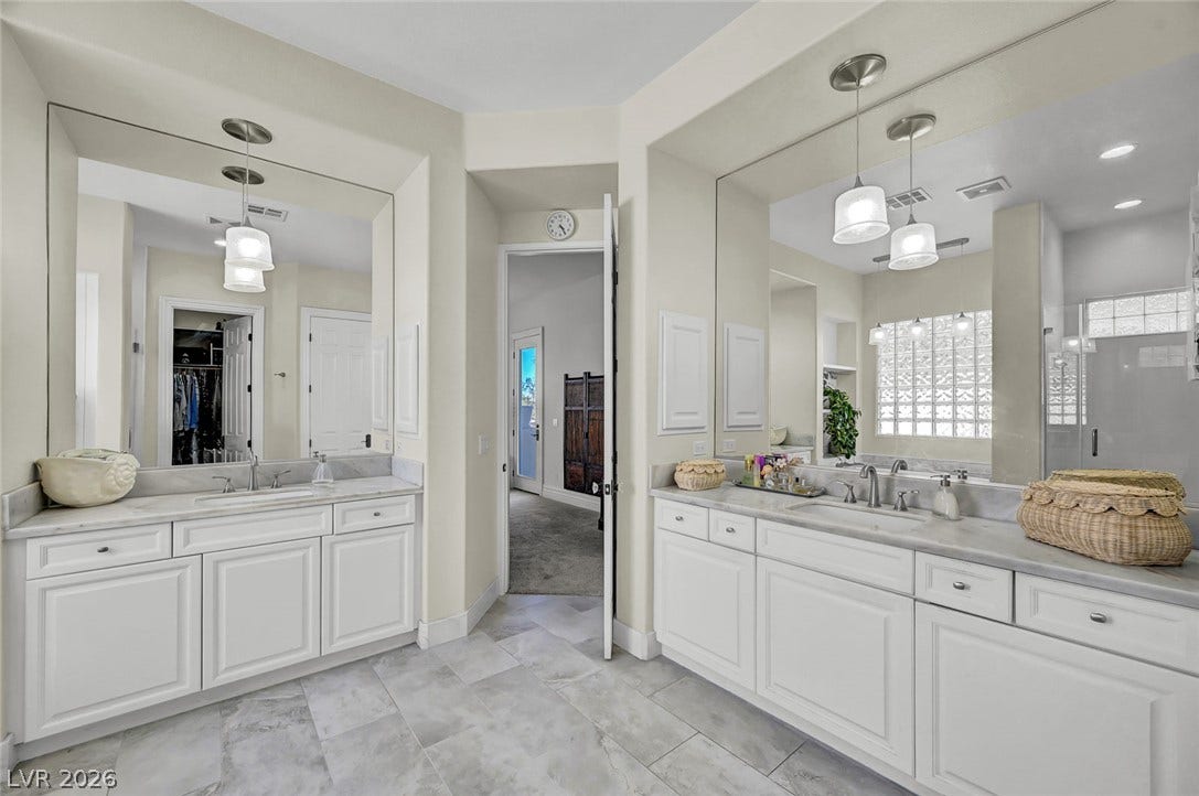 1116 Golden Age Court, Las Vegas, NV 89144 Double vanities with stone counters and tile flooring accent this primary bathroom.