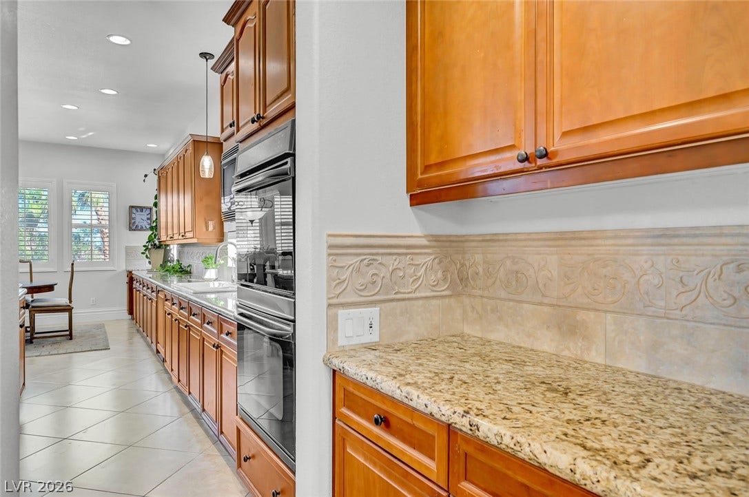 1116 Golden Age Court, Las Vegas, NV 89144 Rich wood cabinetry paired with granite countertops defines this long culinary workspace.
