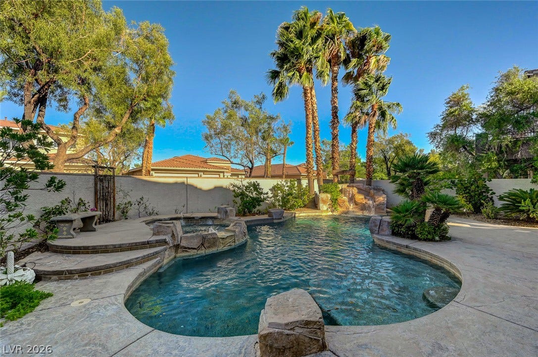 1116 Golden Age Court, Las Vegas, NV 89144 Lush palm trees and natural stone accents frame a backyard swimming pool and spa.