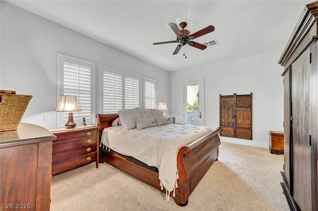 1116 Golden Age Court, Las Vegas, NV 89144 Plentiful natural light fills a spacious bedroom with soft carpeting and direct outdoor access.