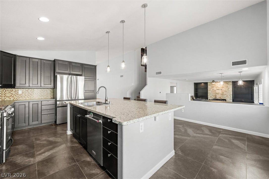 1584 Bozeman Drive, Henderson, NV 89012 Granite countertops and dark cabinetry anchor a bright, open culinary space with modern tile flooring.