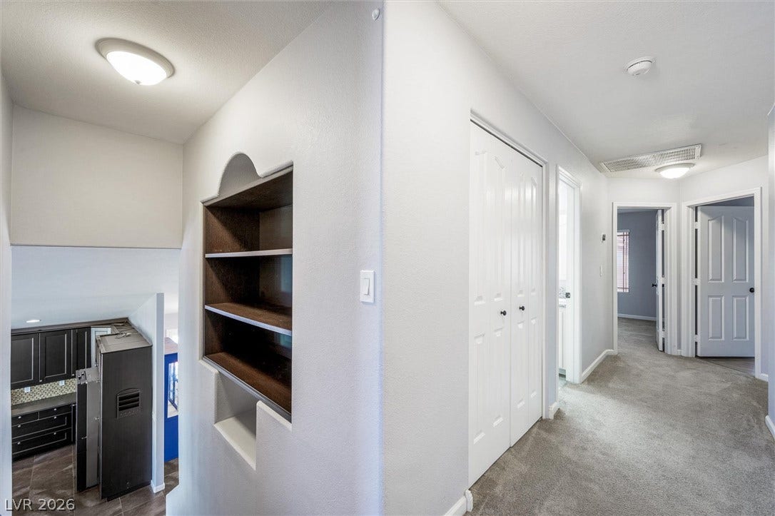 1584 Bozeman Drive, Henderson, NV 89012 An upper-level hallway features built-in shelving, carpet flooring, and custom wall cutouts overlooking the kitchen.