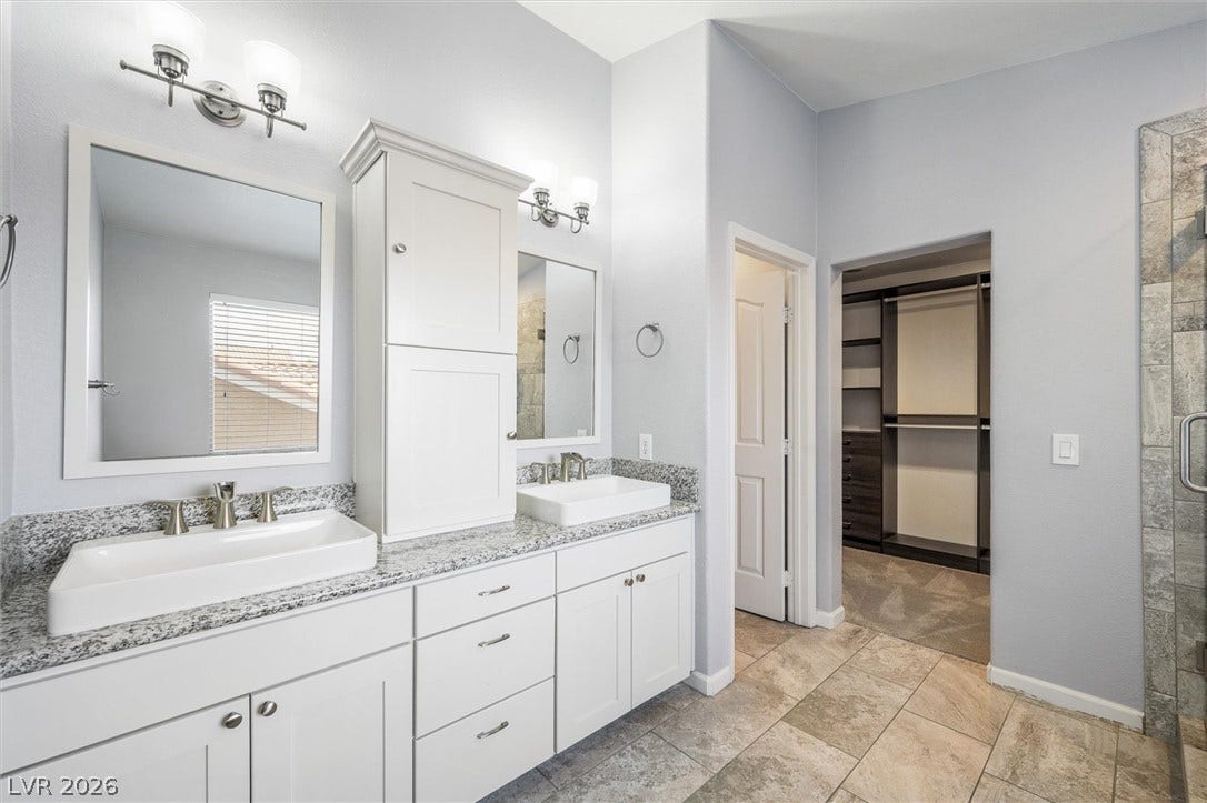 1584 Bozeman Drive, Henderson, NV 89012 Stone counters and custom cabinetry highlight this master bathroom featuring a large walk-in closet.