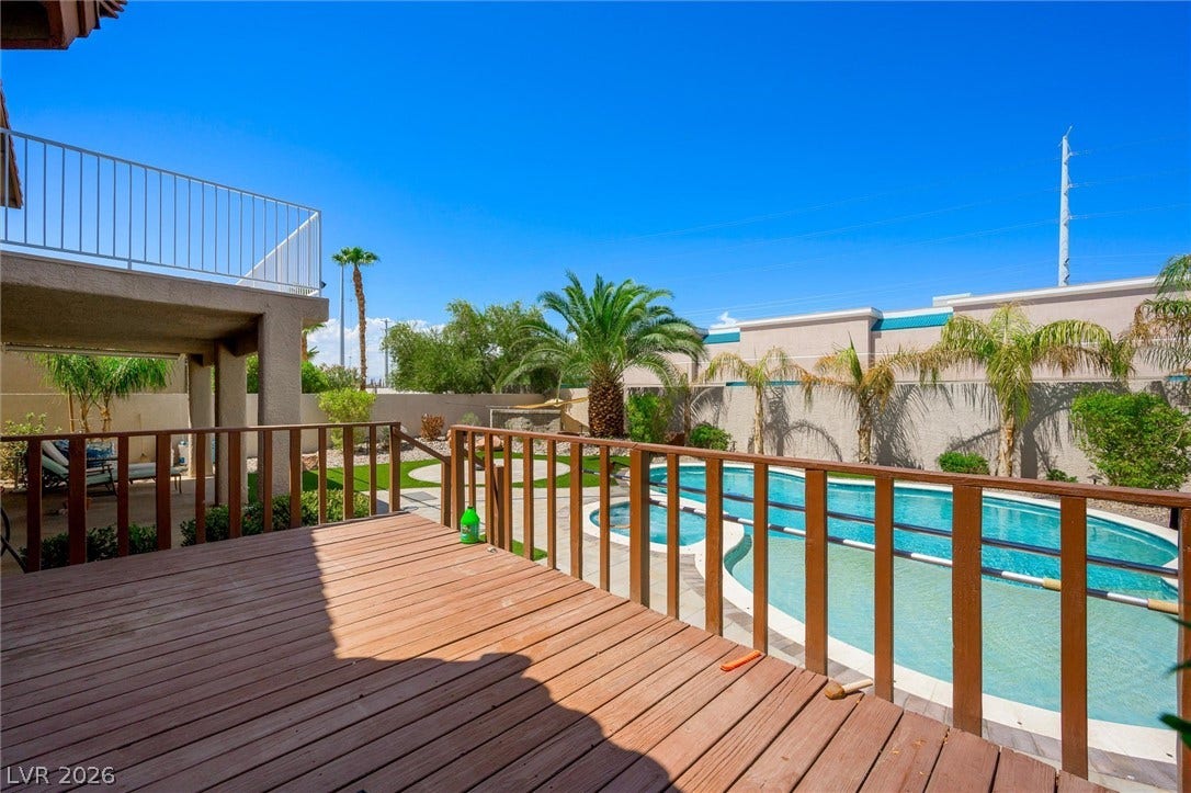 1584 Bozeman Drive, Henderson, NV 89012 An elevated wooden deck overlooks a sparkling backyard pool surrounded by mature palm trees.