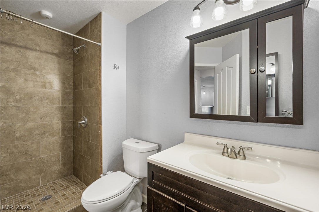 1584 Bozeman Drive, Henderson, NV 89012 Earth-toned tiles line a walk-in shower adjacent to a classic single-sink vanity.
