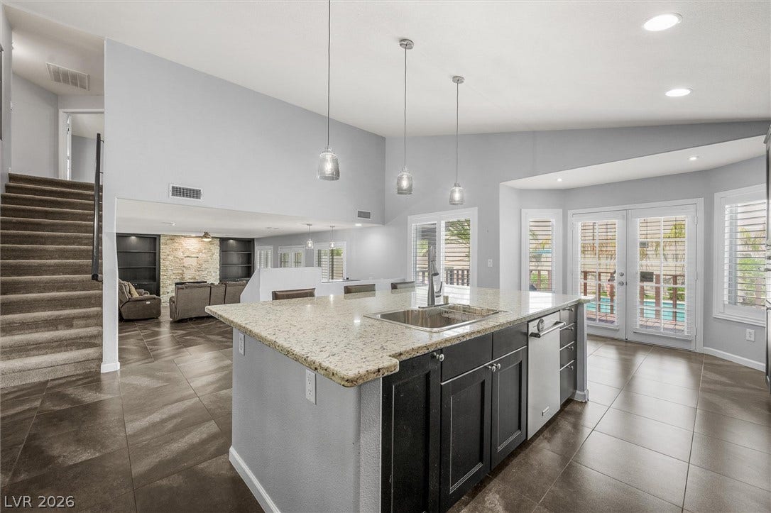 1584 Bozeman Drive, Henderson, NV 89012 Gleaming stone countertops and a spacious breakfast bar highlight this open-concept culinary space.