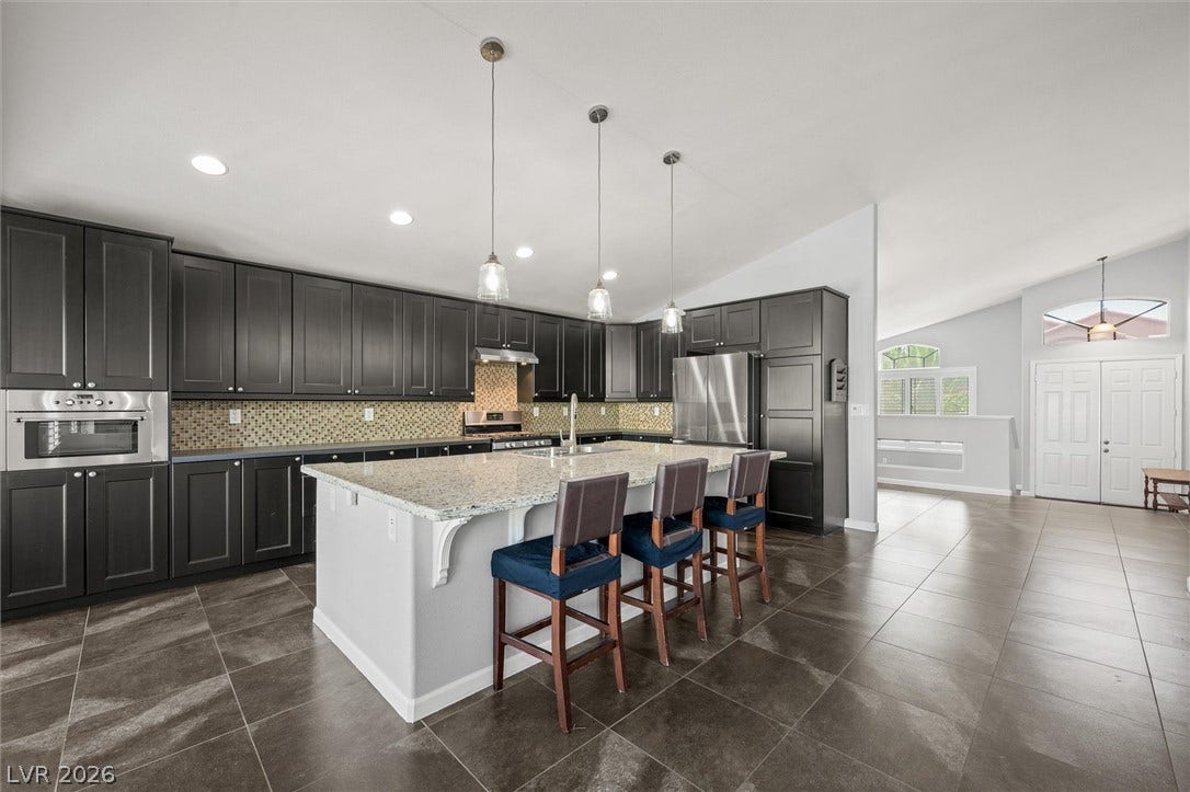 1584 Bozeman Drive, Henderson, NV 89012 Granite countertops and dark cabinetry define this spacious open-concept kitchen.