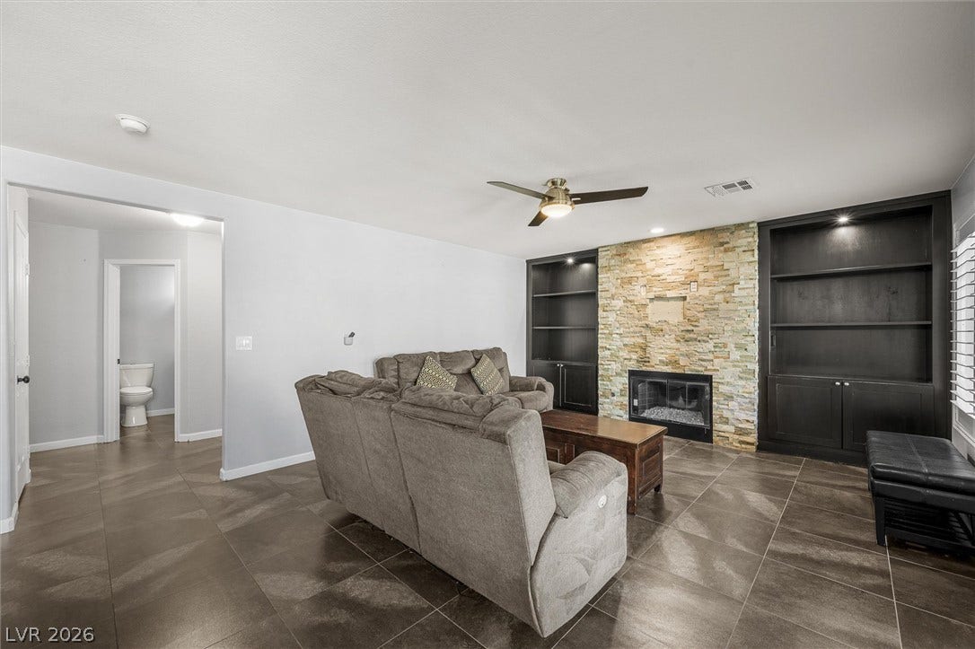 1584 Bozeman Drive, Henderson, NV 89012 Rich tile flooring and a stone-clad fireplace anchor this open living area.