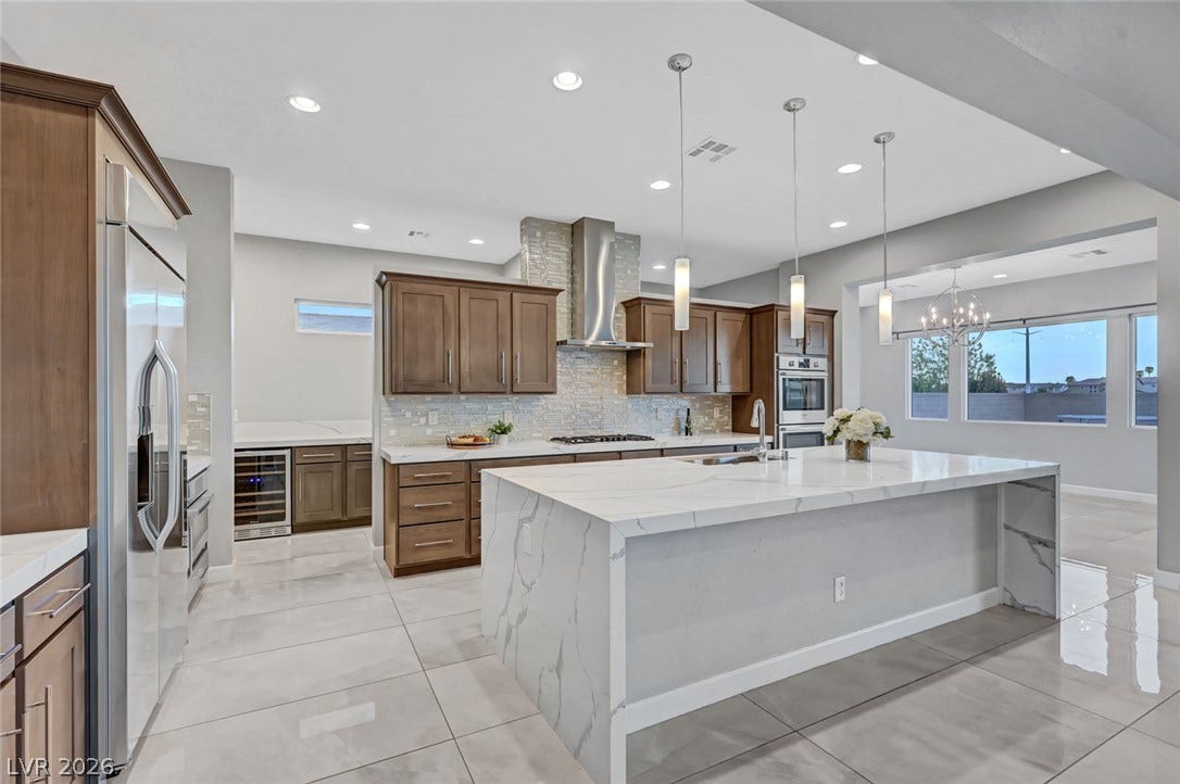 Polished tile flooring and waterfall stone countertops anchor this modern culinary space.