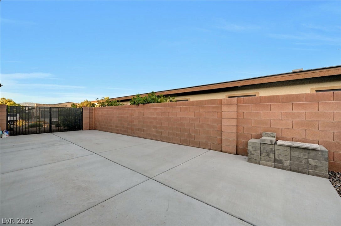 A spacious concrete pad sits enclosed by durable block wall fencing and a metal gate.
