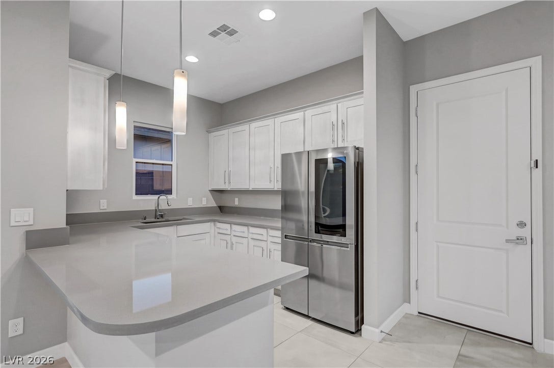 Clean lines and smooth stone countertops define this modern kitchen with stainless steel appliances.