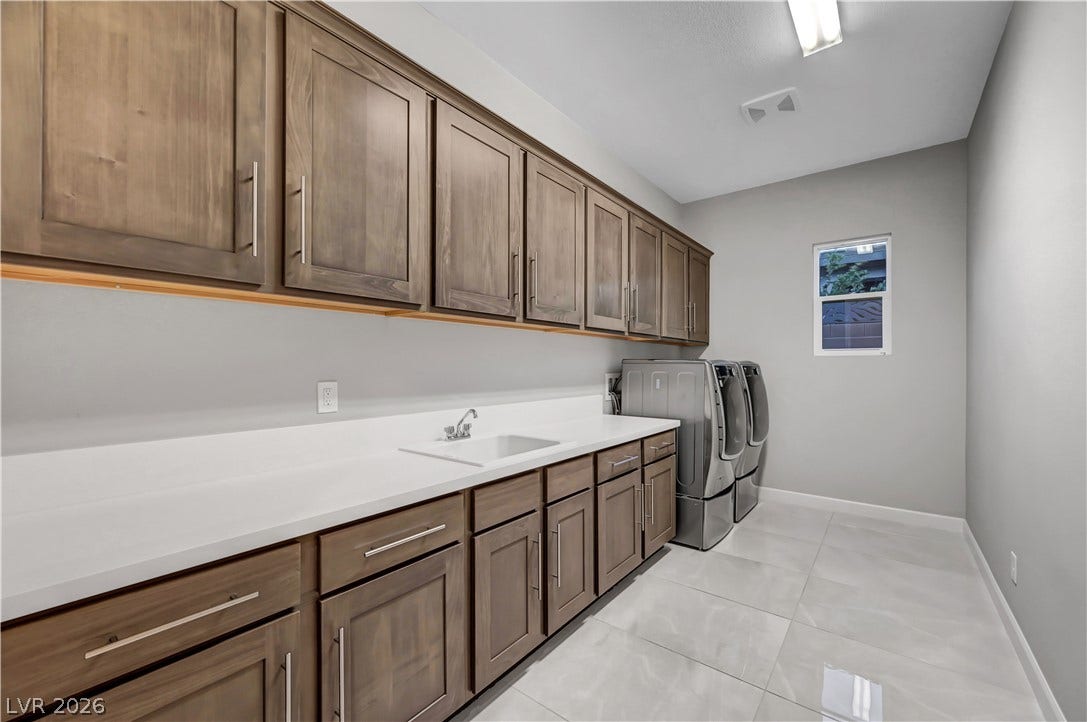 Ample wooden cabinetry and sleek stone countertops define this highly functional utility space.