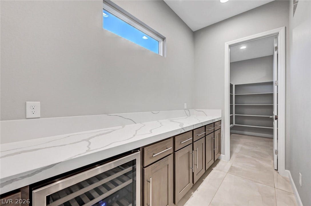 Smooth stone countertops and streamlined cabinetry lead to a spacious walk-in pantry.