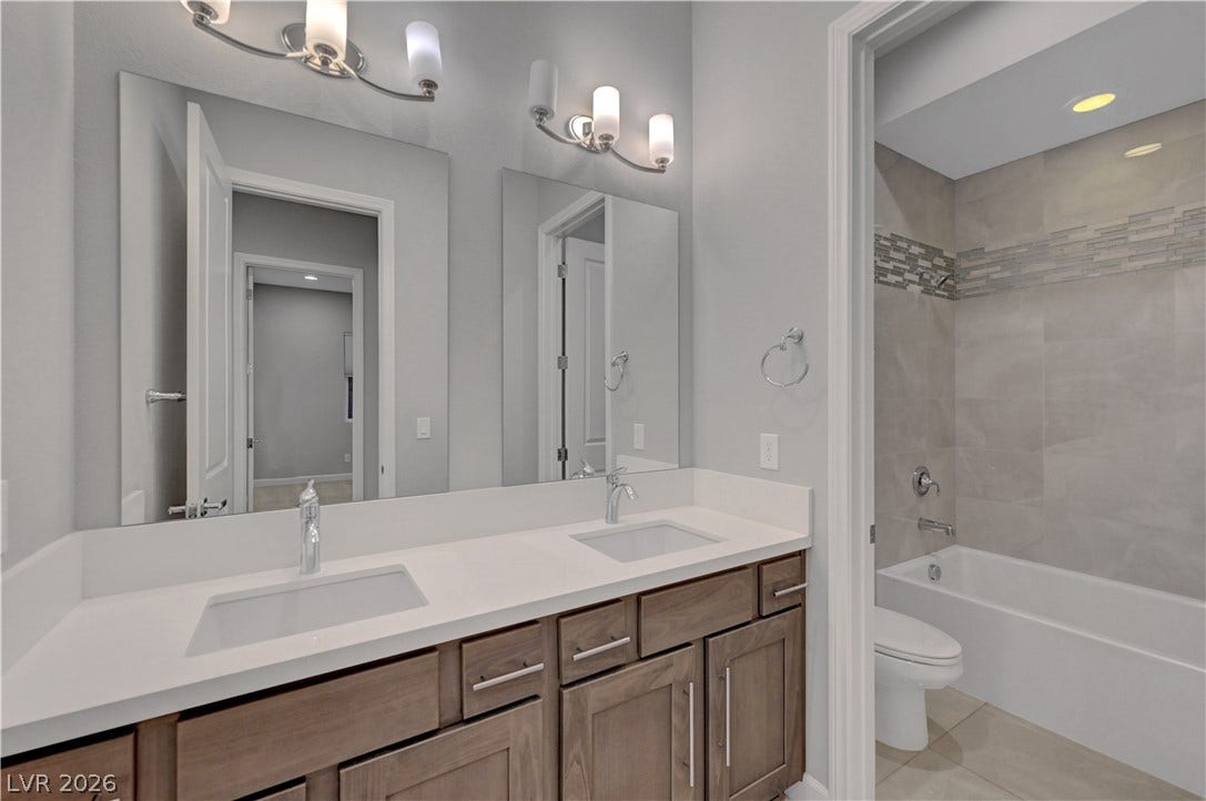 Double vanities and a tiled tub surround highlight this modern, functional bathroom space.