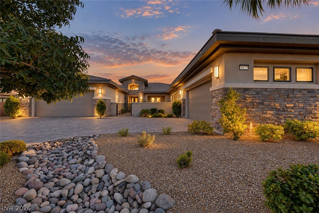 Striking stone accents and integrated lighting define this modern exterior under a sunset sky.