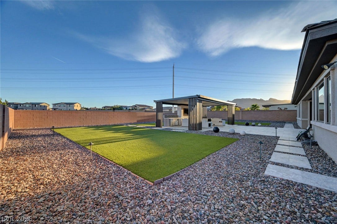 An inviting backyard offers low-maintenance landscaping and a modern detached pergola structure.
