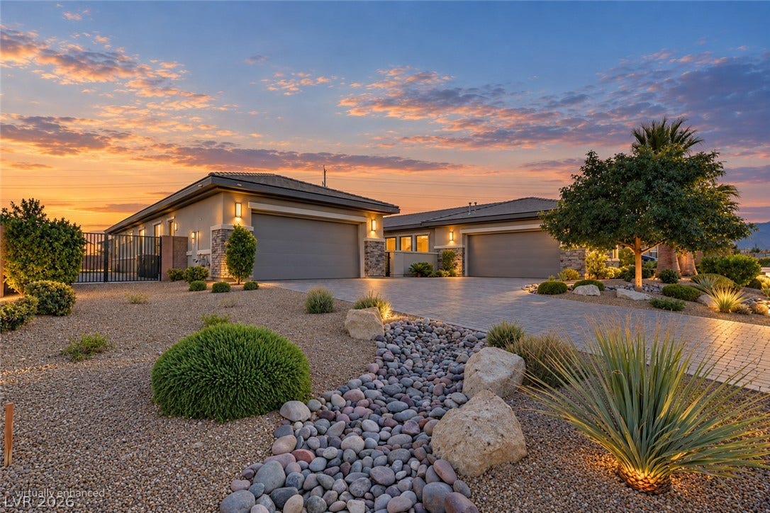 Desert landscaping and a paved driveway lead to this modern single-story exterior.