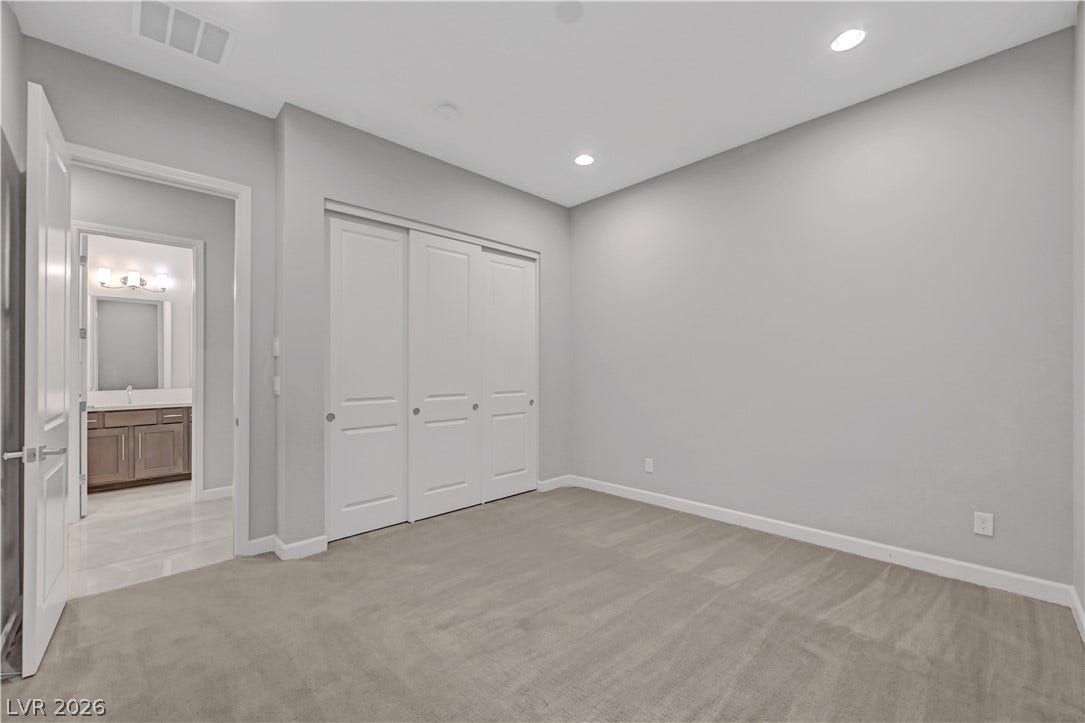 Plush carpeting and recessed lighting create a comfortable atmosphere in this secondary bedroom.