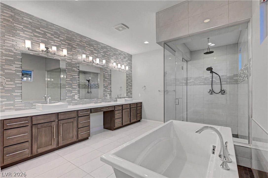 An expansive double vanity and a glass shower surround a luxurious freestanding soaking tub.