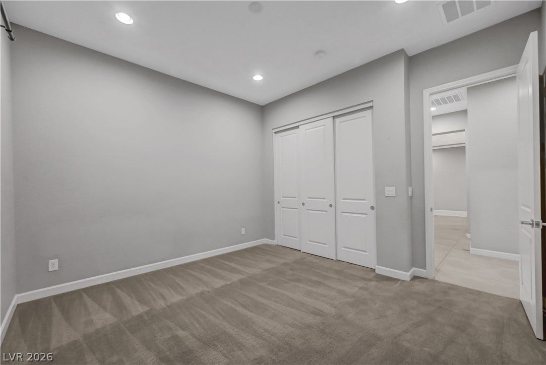 Plush carpeting and recessed lighting create a comfortable atmosphere in this versatile bedroom.