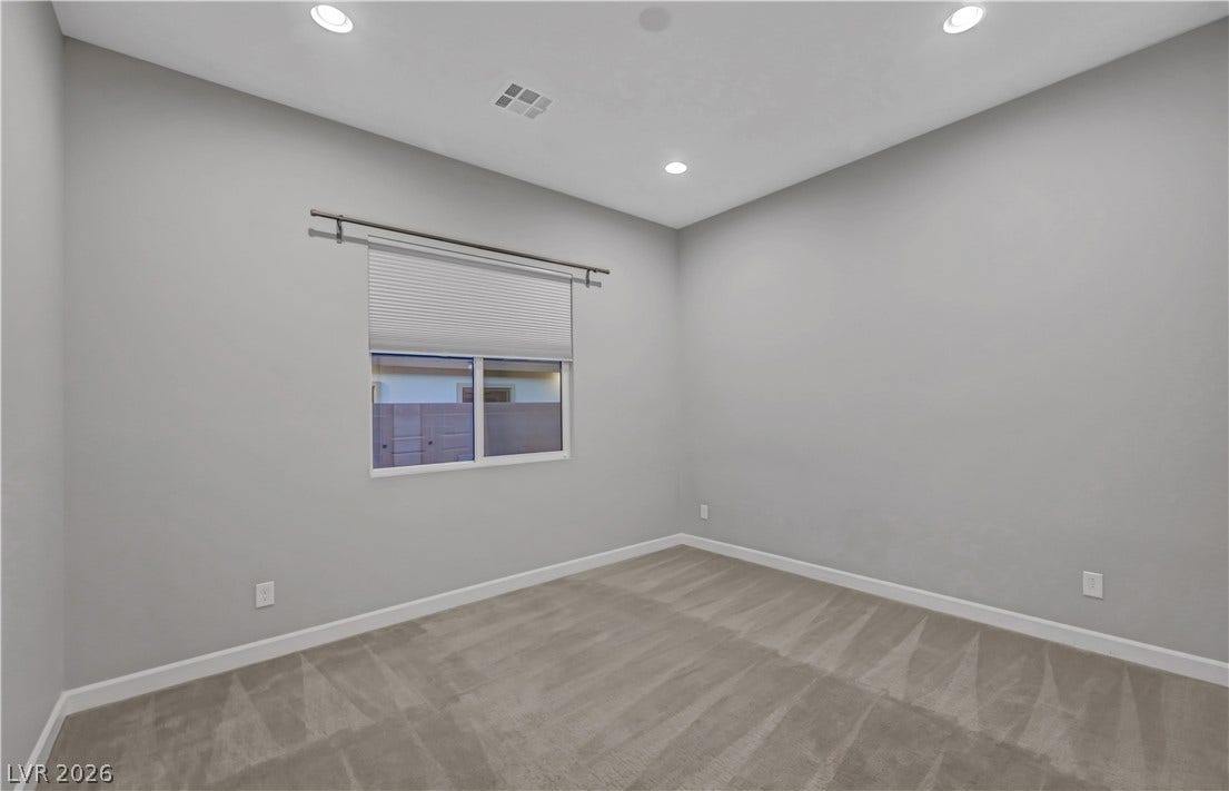 Recessed lighting illuminates this versatile space featuring plush carpeting and a modern window.