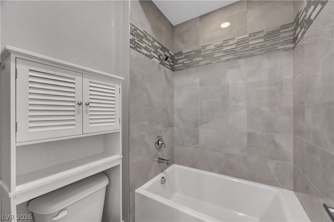 Polished tile walls and an accent border frame the clean lines of this modern alcove tub.