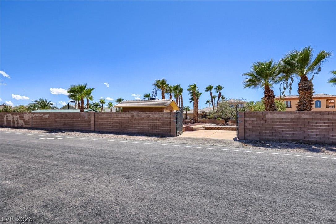 2807 Richmar Avenue, Henderson, NV 89074 Secured gates open to a paved driveway framed by privacy walls and mature palm trees.