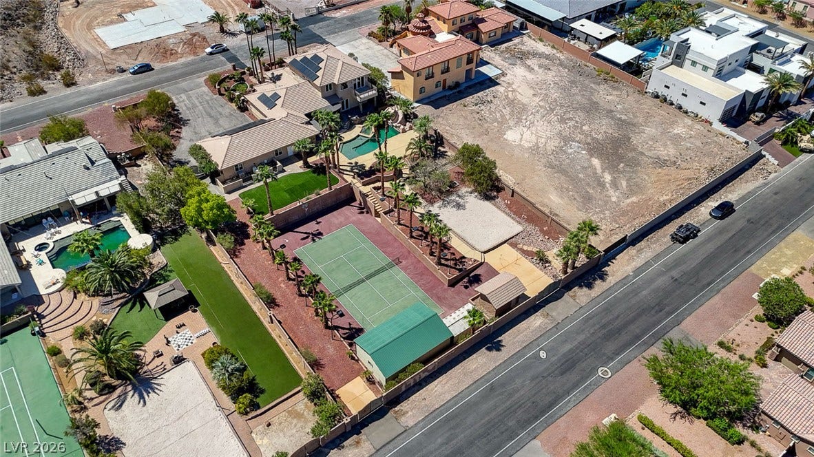 2807 Richmar Avenue, Henderson, NV 89074 An aerial perspective reveals a private tennis court situated among palm trees and adjacent properties.