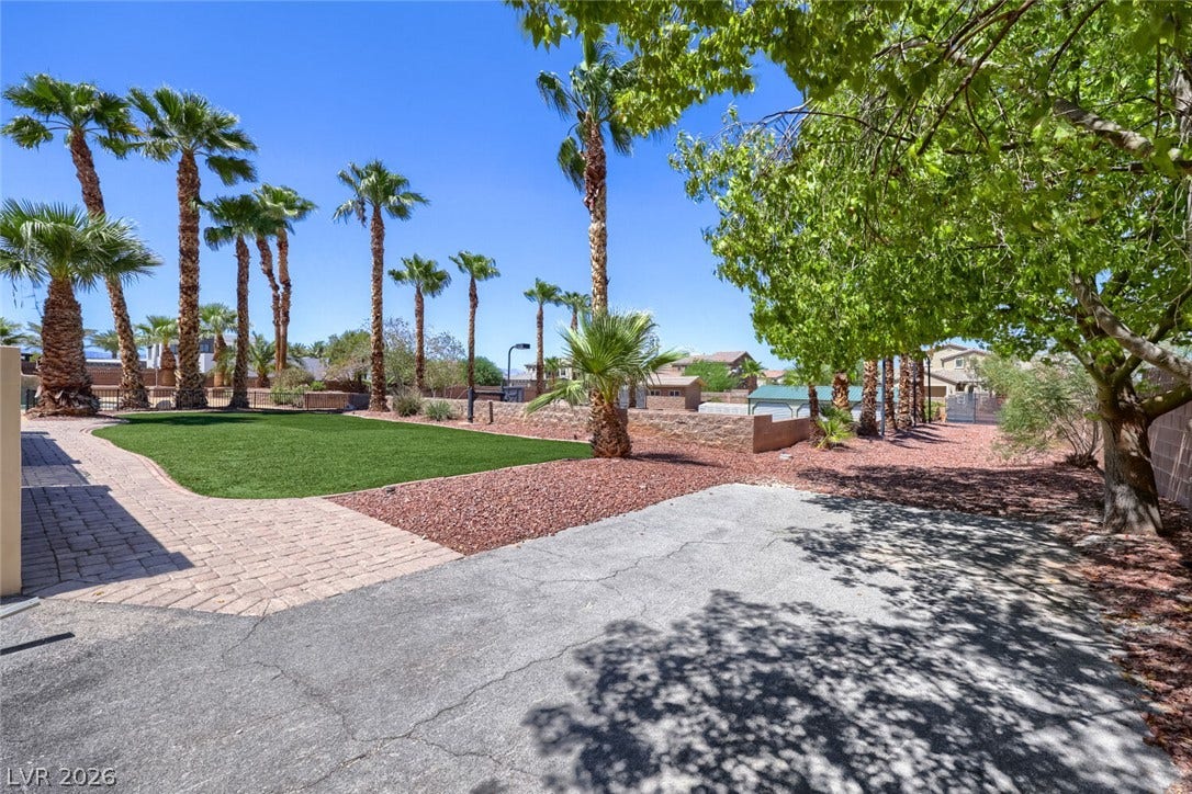 2807 Richmar Avenue, Henderson, NV 89074 Towering palm trees frame a paved pathway and manicured lawn under clear blue skies.
