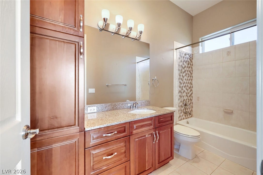2807 Richmar Avenue, Henderson, NV 89074 Rich wood cabinetry paired with granite countertops and tiled bathing area highlights this bathroom.