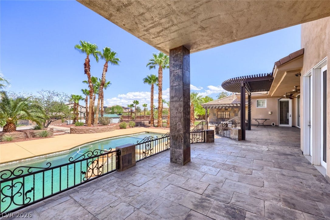 2807 Richmar Avenue, Henderson, NV 89074 An expansive covered patio overlooks a private pool area bordered by palm trees.