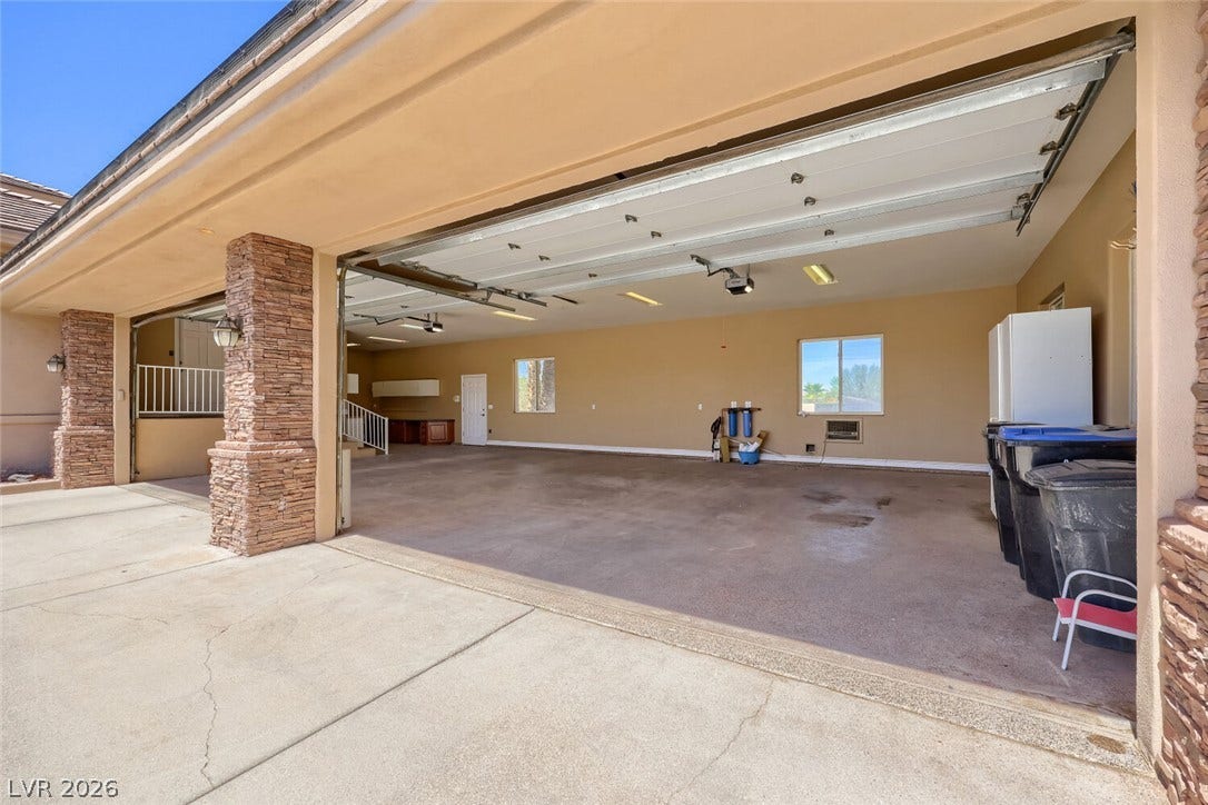 2807 Richmar Avenue, Henderson, NV 89074 Stone pillars frame the wide entrance to a massive multi-car garage with concrete flooring.