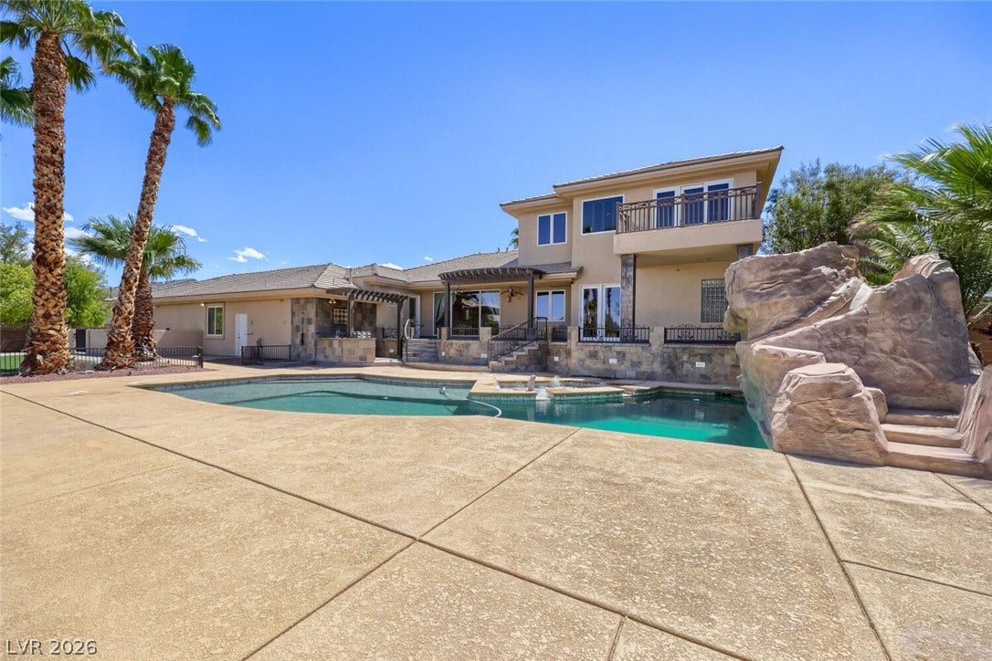 2807 Richmar Avenue, Henderson, NV 89074 A spacious concrete patio surrounds an inviting swimming pool set against a multi-level stucco home.