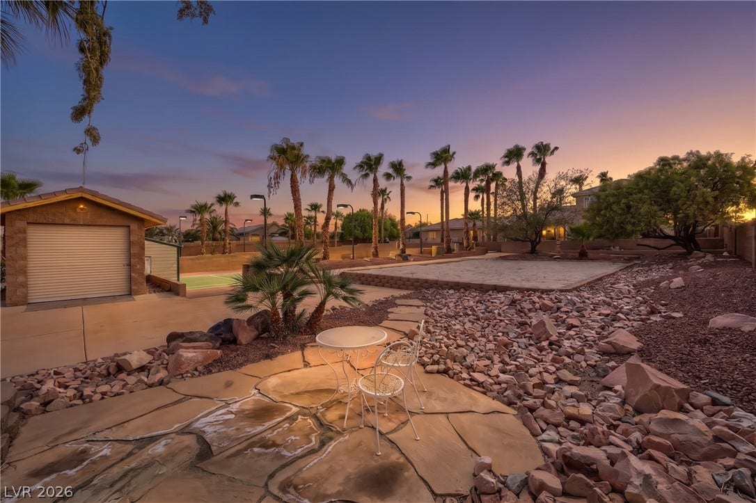 2807 Richmar Avenue, Henderson, NV 89074 Lush palm trees and flagstone paving define this sprawling desert backyard sanctuary under twilight skies.