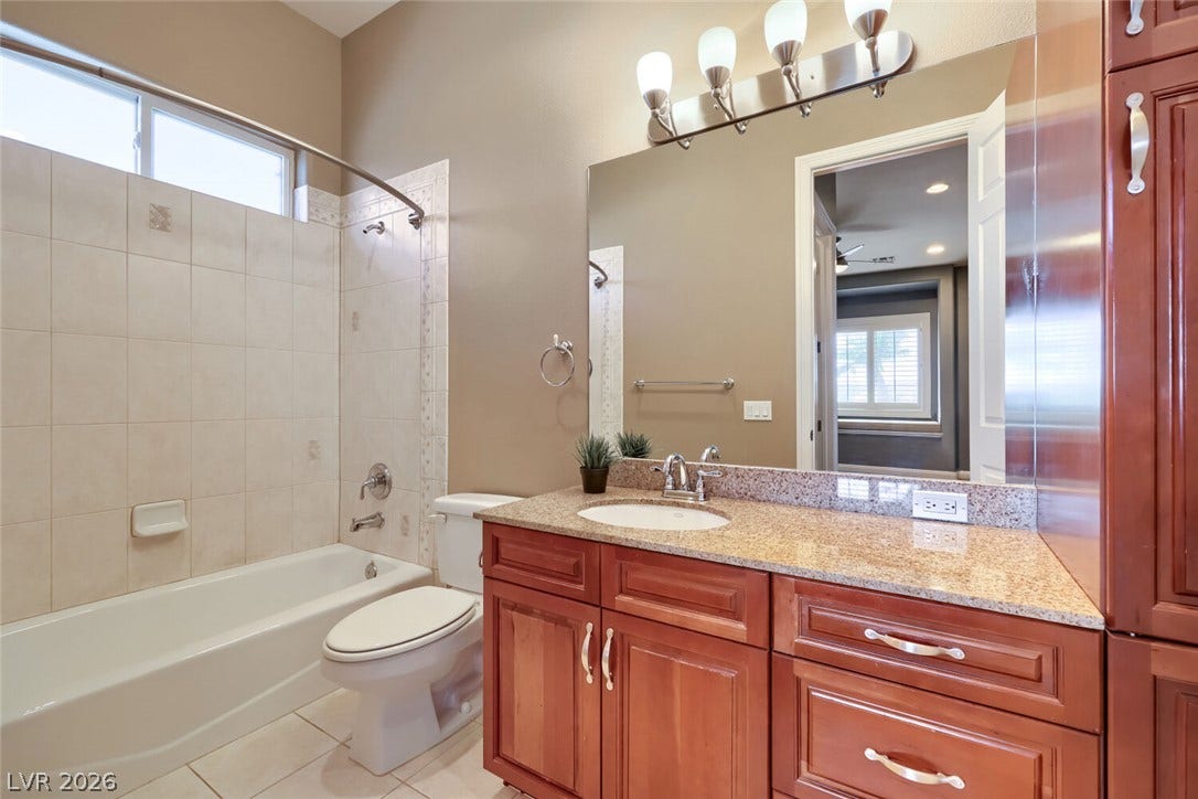 2807 Richmar Avenue, Henderson, NV 89074 Warm wood cabinetry and granite counters define this classic bathroom with integrated shower-tub design.