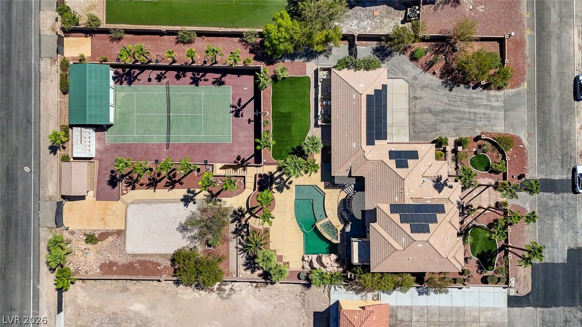 2807 Richmar Avenue, Henderson, NV 89074 An aerial view showcases a tennis court, swimming pool, and solar-paneled roof on this property.