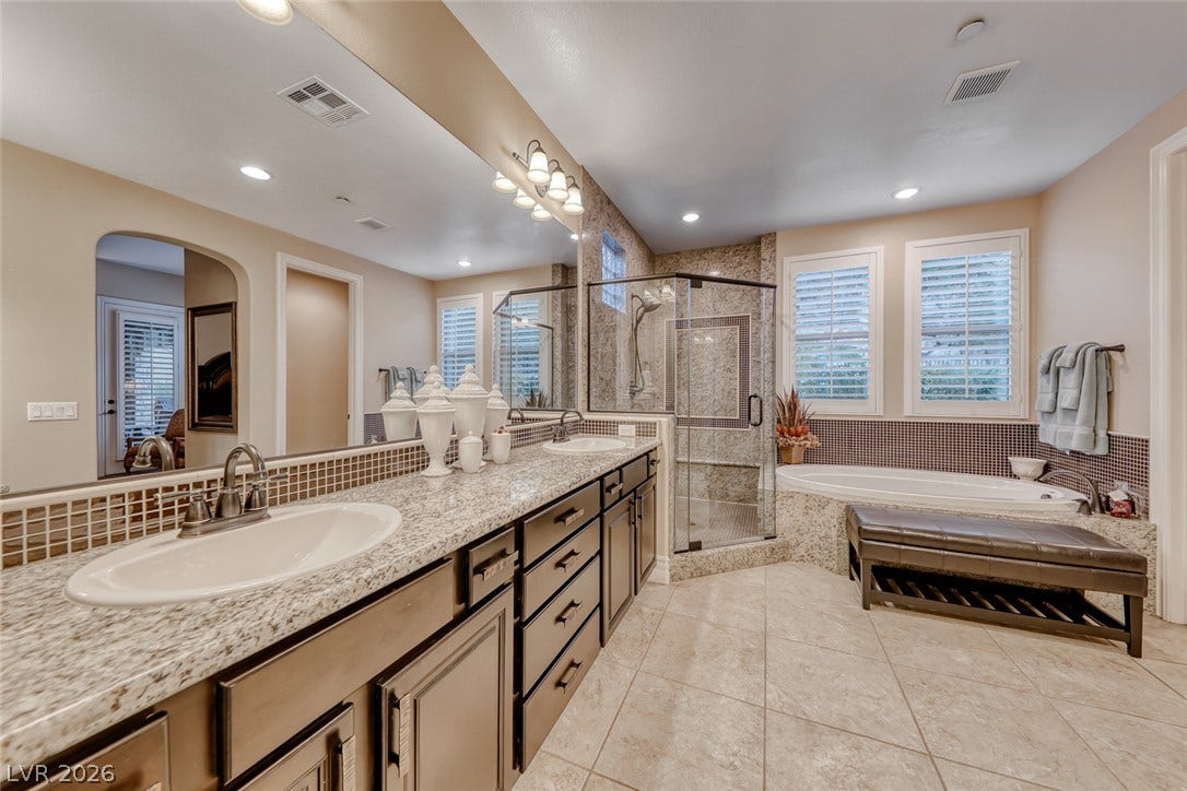 41 Moltrasio Lane, Henderson, NV 89011 Polished tile flooring and expansive stone countertops define this elegant, light-filled bathroom space.