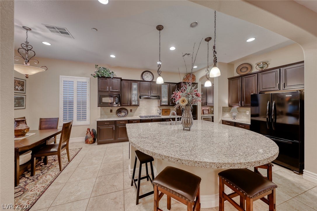 41 Moltrasio Lane, Henderson, NV 89011 Granite countertops and dark cabinetry anchor this kitchen, highlighted by a large curved island.