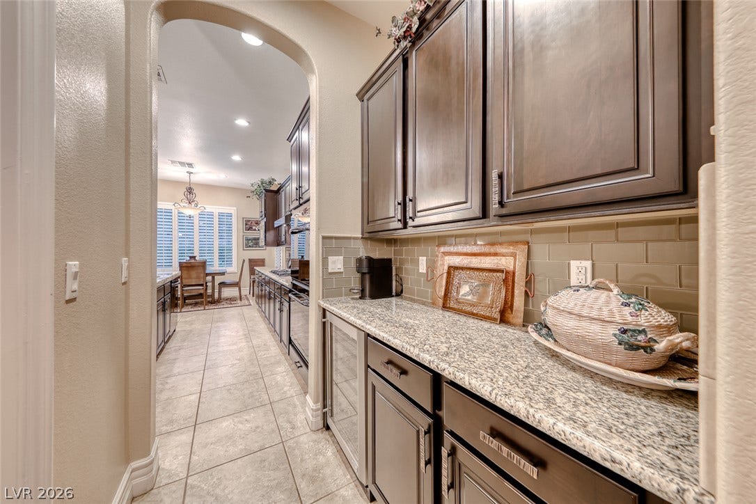 41 Moltrasio Lane, Henderson, NV 89011 An arched doorway opens to a butler pantry featuring granite countertops and custom cabinetry.