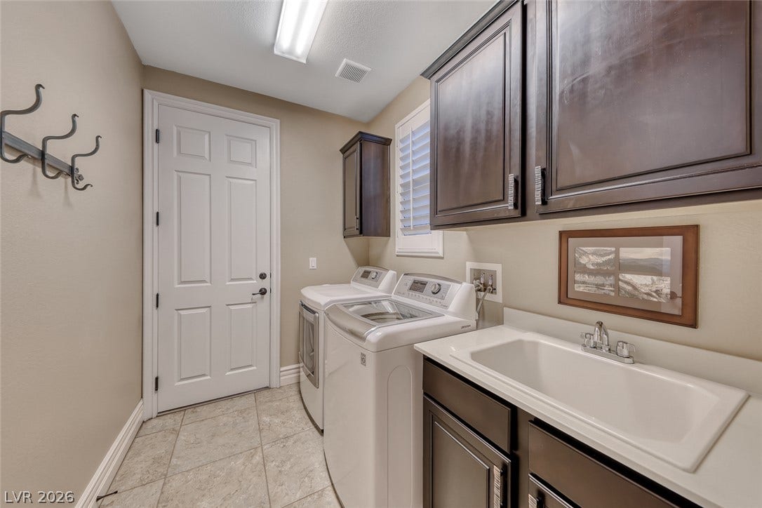 41 Moltrasio Lane, Henderson, NV 89011 A functional laundry area boasts dark wooden cabinetry and a built-in utility sink.