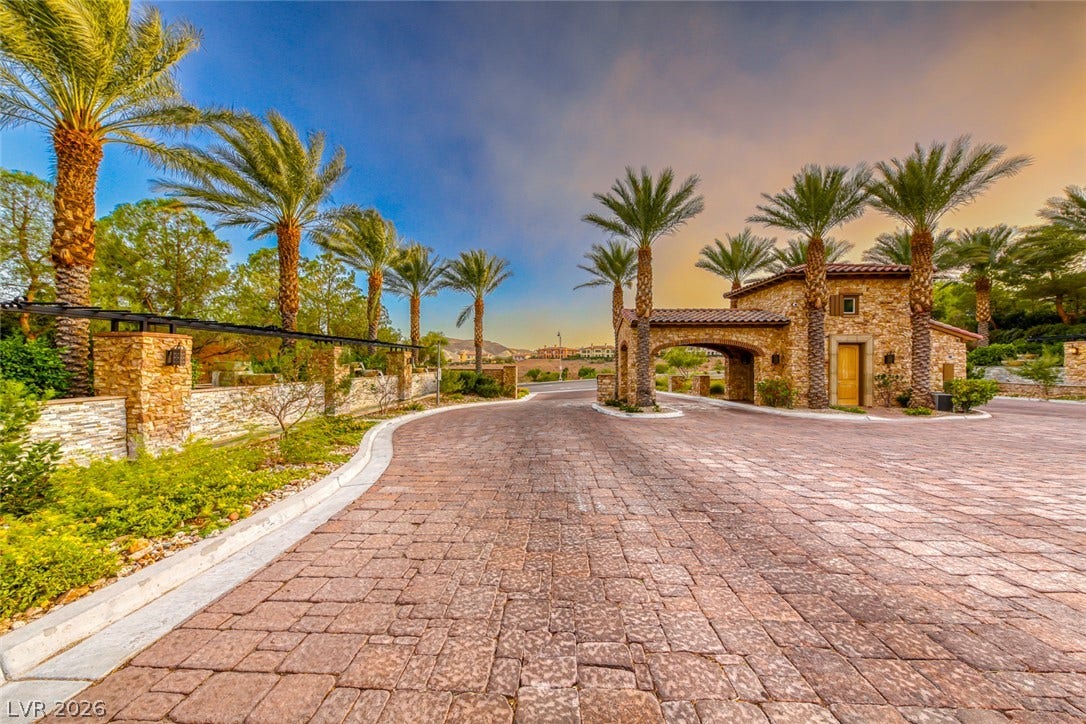 41 Moltrasio Lane, Henderson, NV 89011 An elegant stone guard gate structures the paved entrance under towering palm trees.