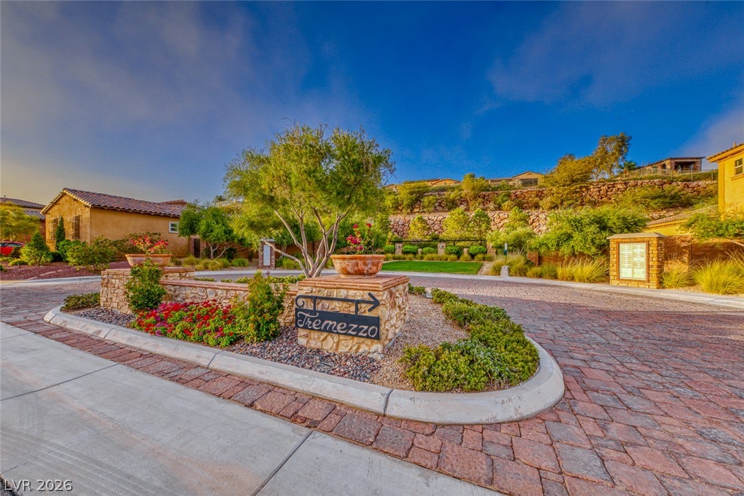 41 Moltrasio Lane, Henderson, NV 89011 Cobblestone streets and manicured stone planters lead into a peaceful residential neighborhood under blue skies.