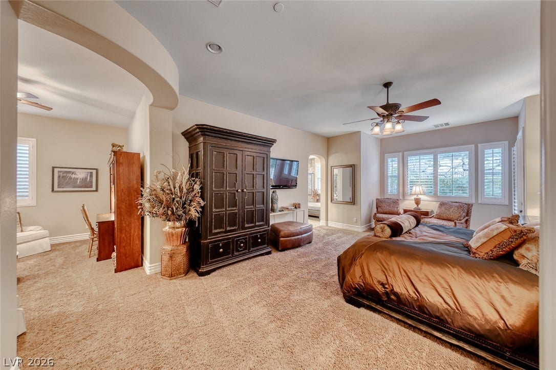 41 Moltrasio Lane, Henderson, NV 89011 An arched entryway leads into a carpeted bedroom suite under recessed lighting.