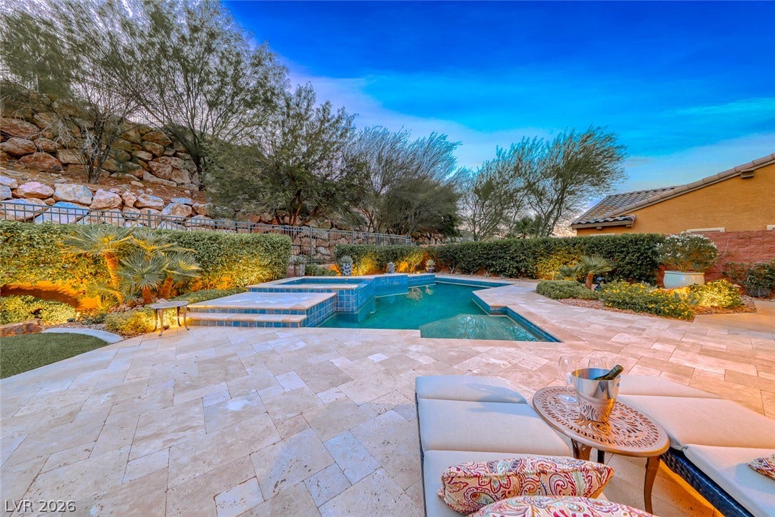 41 Moltrasio Lane, Henderson, NV 89011 An inviting backyard oasis features a shimmering pool framed by lush, illuminated landscaping.