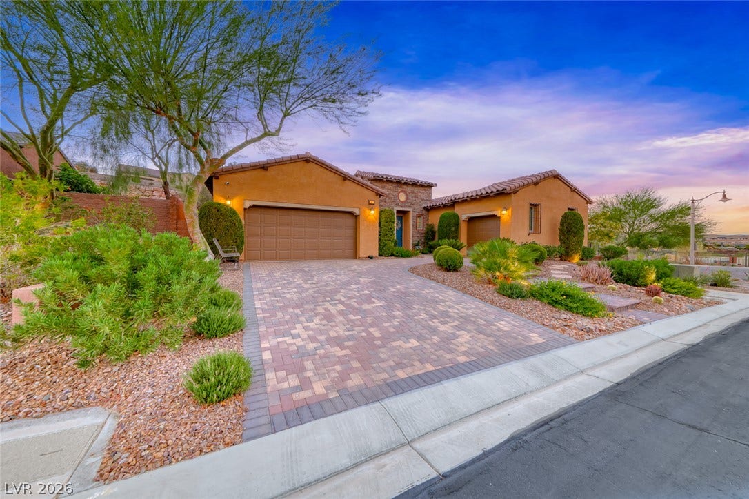 41 Moltrasio Lane, Henderson, NV 89011 A handsome paver driveway leads to this stone-accented desert home under a twilight sky.